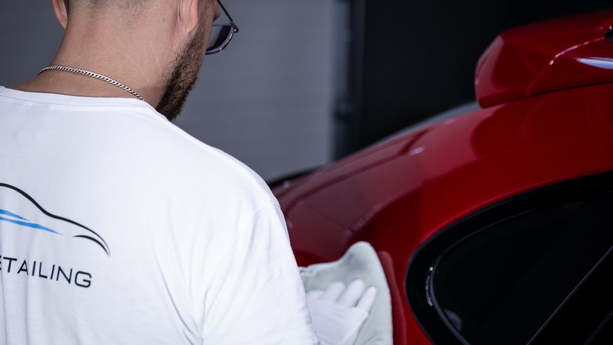 Handarbeit an der Lackfläche eines roten Sportwagens bei Indigo Detailing